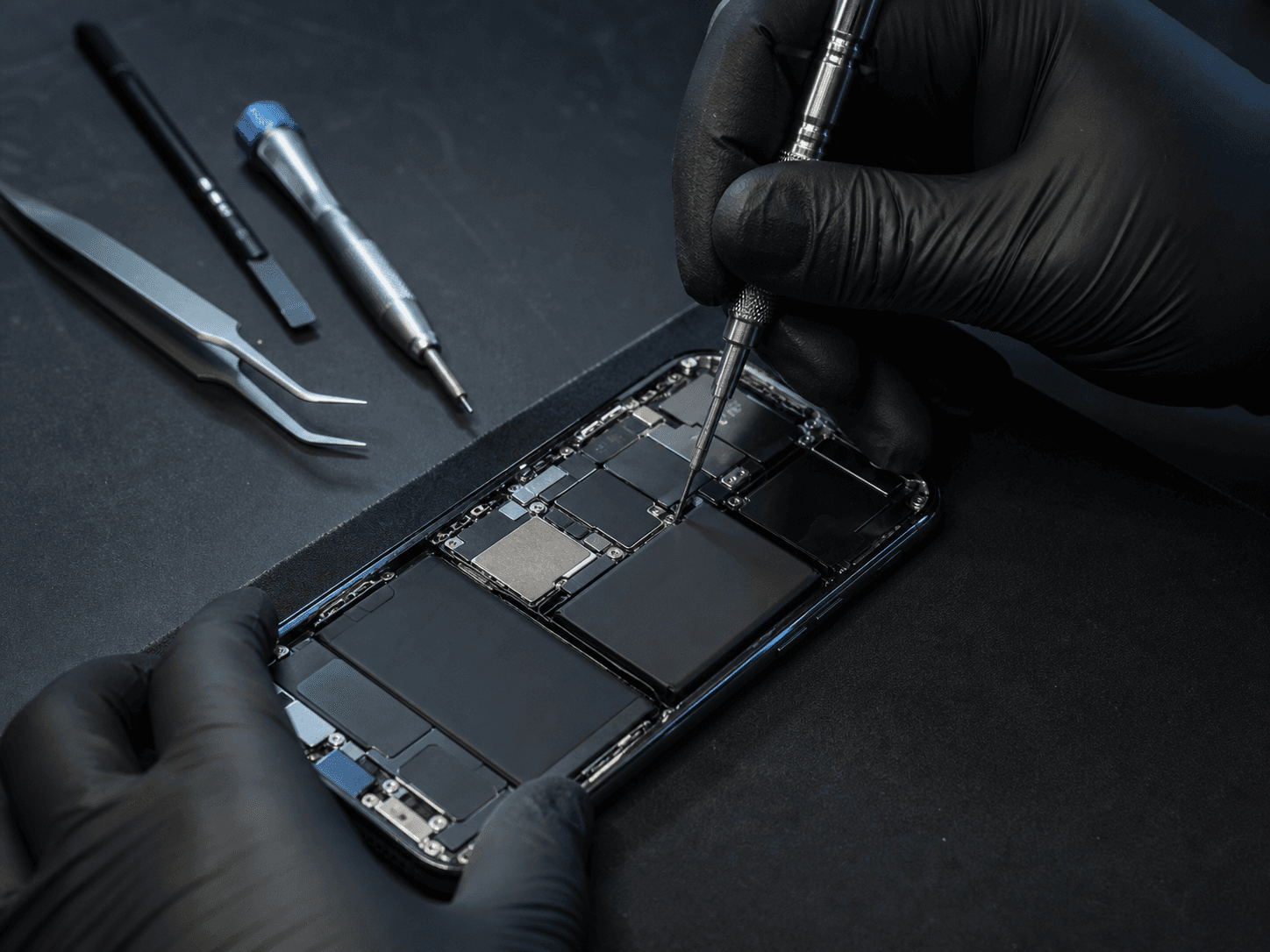Técnico consertando um celular aberto em uma bancada de precisão